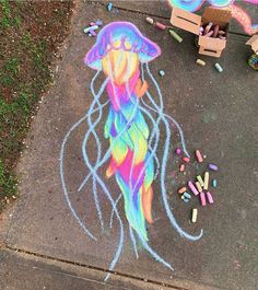 a chalk drawing of a jellyfish with crayons on the ground next to it