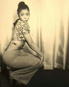 an old black and white photo of a woman sitting on a stool