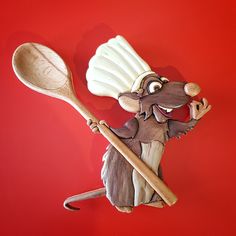 a statue of a mouse holding a wooden spoon