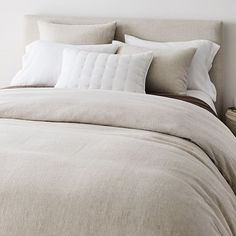 an unmade bed with white linens and pillows