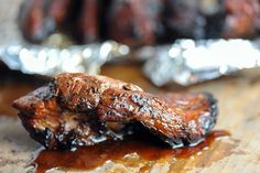 two pieces of meat sitting on top of tin foil covered in bbq barbecue sauce