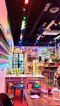 the interior of a restaurant with tables, chairs and shelves filled with drinks on display