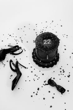 a black and white photo of a 21st birthday cake surrounded by shoes, umbrellas and other accessories