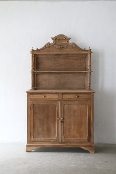 an old wooden cabinet with carvings on the top and bottom, against a white wall