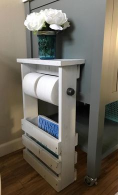 a white flower in a vase sitting on top of a wooden shelf next to a wall