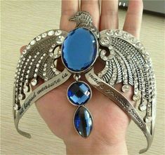 an image of a woman's hand holding a brooch with blue stones on it