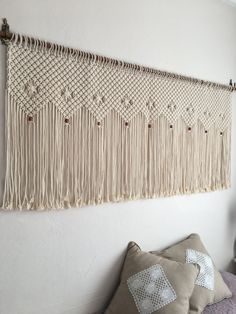 a wall hanging made out of macrame beads and tassels on a white wall