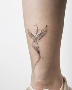 a woman's leg with a small tattoo on the back of her leg, and a whale tail