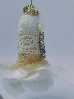 a crocheted object is sitting on top of a white flowered cloth with beads