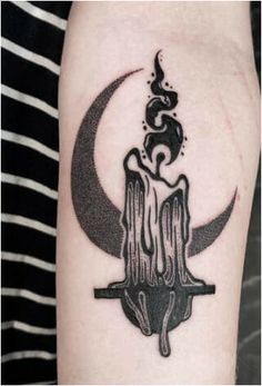 a black and white tattoo on the arm of a person with a crescent, moon and cross