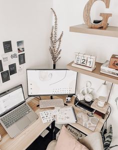 a desk with two laptops and a desktop computer on it in front of a white wall