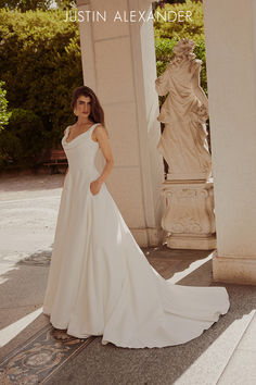 a woman in a white wedding dress standing next to a pillar with statues behind her