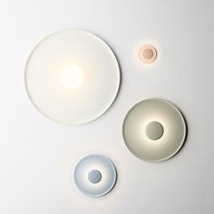 three circular lights are shown on a white surface, one is dimmer and the other is off