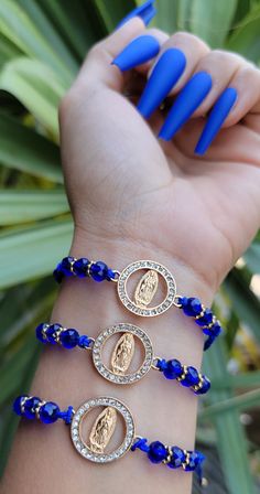 a woman's hand with three blue bracelets on her wrist and two gold medallions