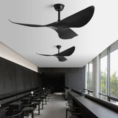 the ceiling fans are hanging from the ceiling in this room with black tables and chairs