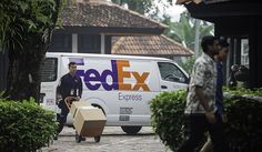 a fedex truck parked in front of a building with two men walking by it