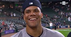 a baseball player is smiling in front of the stands at a game and people are looking on