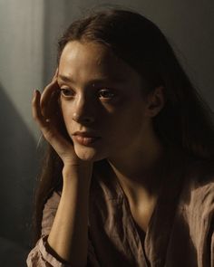 a woman sitting down with her hand on her head and looking off to the side