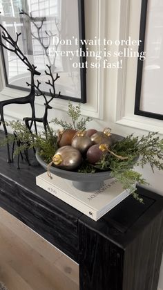 a bowl filled with ornaments sitting on top of a black table next to a window