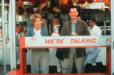 two people standing behind a sign that says we're talking