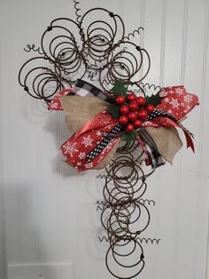 a red and white christmas decoration hanging on a door with metal spirals around it