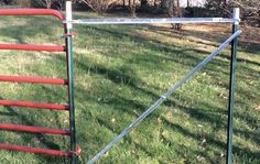 a red and green metal fence in the grass