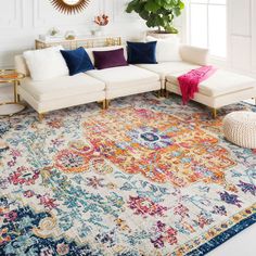 a living room with white couches, colorful rug and large mirror on the wall