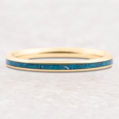 a yellow gold band with blue stones on the inside and outside, sitting on a white surface