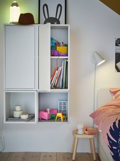 a bed room with a neatly made bed and white cupboards on the wall above it