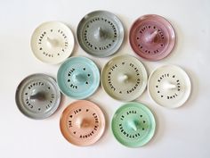 seven ceramic bowls with words on them arranged in the shape of a circle, all different colors and sizes