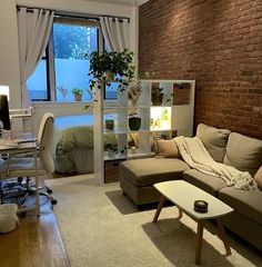 a living room filled with furniture and a brick wall behind the couch is a bed