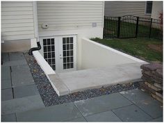 an outside view of a house with a door and window in the ground next to it