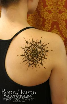 the back of a woman's shoulder with an intricate tattoo design on her upper arm