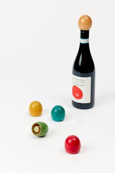 a bottle of wine and three colorful balls on a white surface with a wooden top