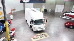 a white truck parked inside of a garage next to other cars and boats on display