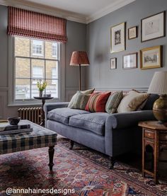 a living room filled with furniture and pictures on the wall next to a window covered in curtains