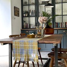 a dining room table and chairs with a plaid table cloth on it