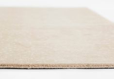 a close up view of a beige rug on a white surface with no one around it