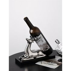 a bottle of wine sitting on top of a table next to a silver cat figurine