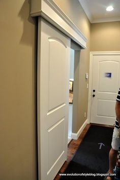 a man is standing in front of a white door and looking at the hallway way