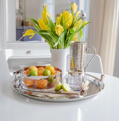 a tray with lemons, oranges and tulips sitting on a table