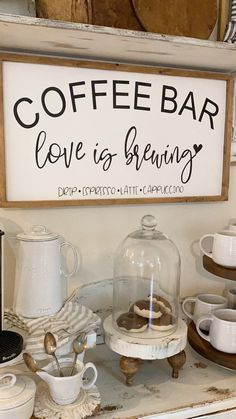 a coffee bar sign on the wall above a counter with cups and saucers in front of it