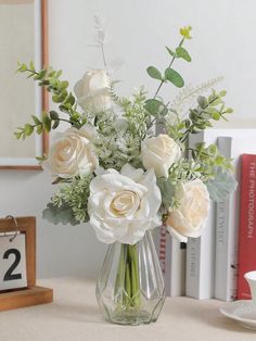 a vase filled with white flowers sitting on top of a table next to a clock