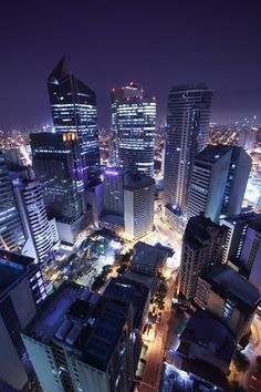 an aerial view of the city at night with skyscrapers lit up and buildings in the foreground