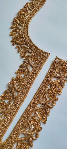 two pieces of gold jewelry on a white surface