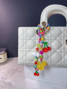 This neon tone colorful beaded bag features a rich and vibrant palette, giving it an overall bright appearance. It has adorable designs including a rubber duck, a chubby cloud, and charming cherries that everyone loves. It looks cheerful and beautiful, while also being very cute. The bag is versatile and unique, making it a delightful gift. ❤Its length is approximately 48 centimeters. Please note that, due to handmade craftsmanship and measurements, there may be a discrepancy of 1-2 centimeters, Cute Handmade Multicolor Keychains, Trendy Multicolor Handmade Keychains, Multicolor Keychain Bag Charm As Gift, Multicolor Keychain Bag Charm For Gift, Multicolor Beaded Keychains For Everyday Use, Trendy Multicolor Rectangular Keychain, Fun Multicolor Keychains For Gifts, Yellow Chakra, Beaded Cherry