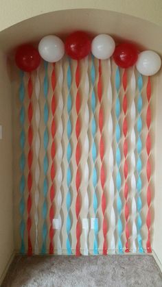 some balloons are hanging from the ceiling in front of a curtain with wavy lines on it