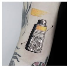 a person with a tattoo on their arm has a yellow substance in the shape of a bottle