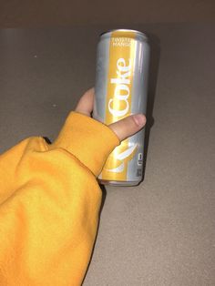 a person holding onto a can of coke