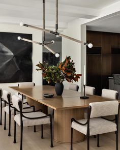 a dining room table with chairs and a vase filled with flowers on top of it